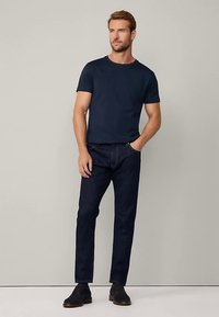 Granatowy t-shirt z krótkim rękawem w połączeniu z ciemnymi dżinsami. Dżinsy mają prosty krój nogawek i subtelne detale przeszyć.