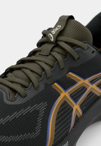 Black athletic shoe with a textured upper, featuring olive green laces and a prominent orange and blue pattern on the side.