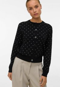 Černý cardigan s bílými puntíky, kulatým výstřihem, předními knoflíky, žebrovanými manžetami a lemem, vyrobený z pleteného materiálu.
