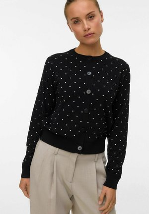 Cardigan nero con pois bianchi, scollo rotondo, bottoni frontali, polsini e orlo a coste, in texture lavorata a maglia.