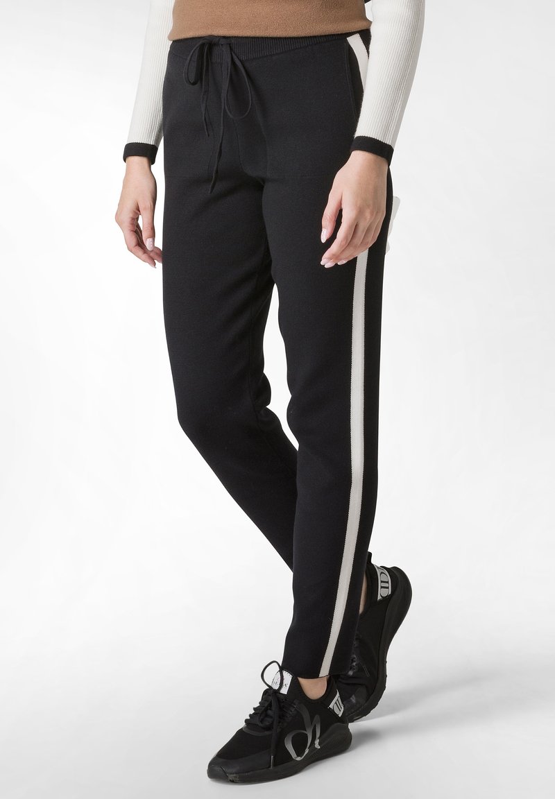 Zwarte joggingsbroek met witte zijstrepen, met een tailleband met trekkoord, slim fit en een gladde stofstructuur. Gemaakt met zwarte sneakers.
