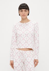 Μπλούζα πιτζάμα με μακριά μανίκια από λευκό ύφασμα με floral σχέδιο μικρών ροζ φιόγκων και τριαντάφυλλων, με κοντό μήκος και απαλό υφασμάτινο υλικό.