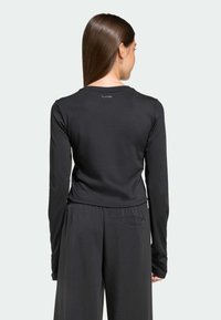Čierne tričko s dlhými rukávmi, okrúhlym výstrihom a priliehavým strihom, s visačkou "CLIMACOOL" na hornej časti chrbta. Mäkká, elastická tkanina.