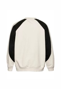 Kosegenser i krem med svarte raglan-ermer. Mykt stoff, ribbestrikket krage og hem, samt sømløst skulderdesign.