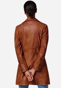 Bruine leren trenchcoat met een op maat gemaakte ontwerp, schouderklappen en knoopdetails op de mouwen, gezien van achteren.