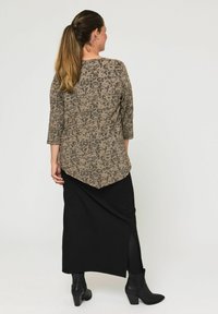 Barna, hosszú ujjú felső, amely texturált, virágmintás, fekete szoknyával párosítva, oldalsó hasítékkal és bokacsizmával.