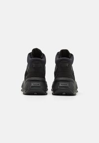 Baskets montantes noires en tissu texturé et caoutchouc, dotées d'un col rembourré, d'un talon renforcé et d'un design unique de la semelle extérieure.