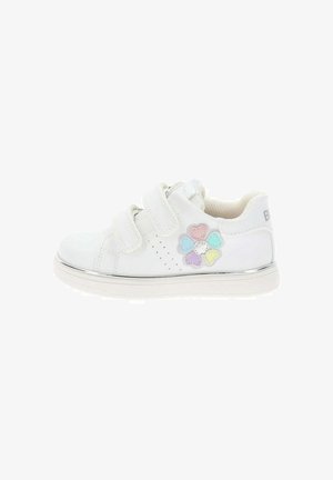 Zapatilla blanca para niños con dos tiras de velcro y una decoración de flor en forma de corazón de colores pastel en el lateral.