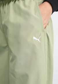 Light green, lightweight pants with a smooth texture, featuring an elastic waistband and a small white Puma logo on the left side.