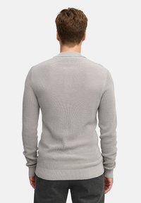 Maglione grigio a maniche lunghe in maglia con trama testurizzata, polsini e orlo a coste. La vista posteriore mostra un collo a giro e un sottile accento con Logo.
