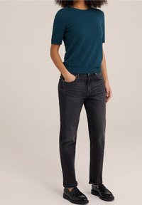 Teal strukturerad stickad tröja med korta ärmar, kombinerad med högmidjade mörkgrå jeans och svarta loafers. Enkel, avslappnad outfit.