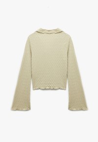 Lichtbeige lange mouw top met een gegolfd textuurpatroon, cropped lengte en een kraag. Beschikt over uitlopende mouwen en een geschulpte zoom.