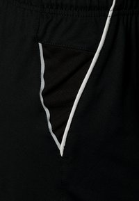 Shorts de sport noirs avec une poche latérale, doublée d'un noir contrastant et bordée de blanc sur les bords. Texture de tissu lisse.