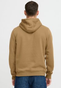 Brown hoodie with a drawstring hood, ribbed cuffs, and hem. Smooth texture, relaxed fit, and stitching detail at the back.