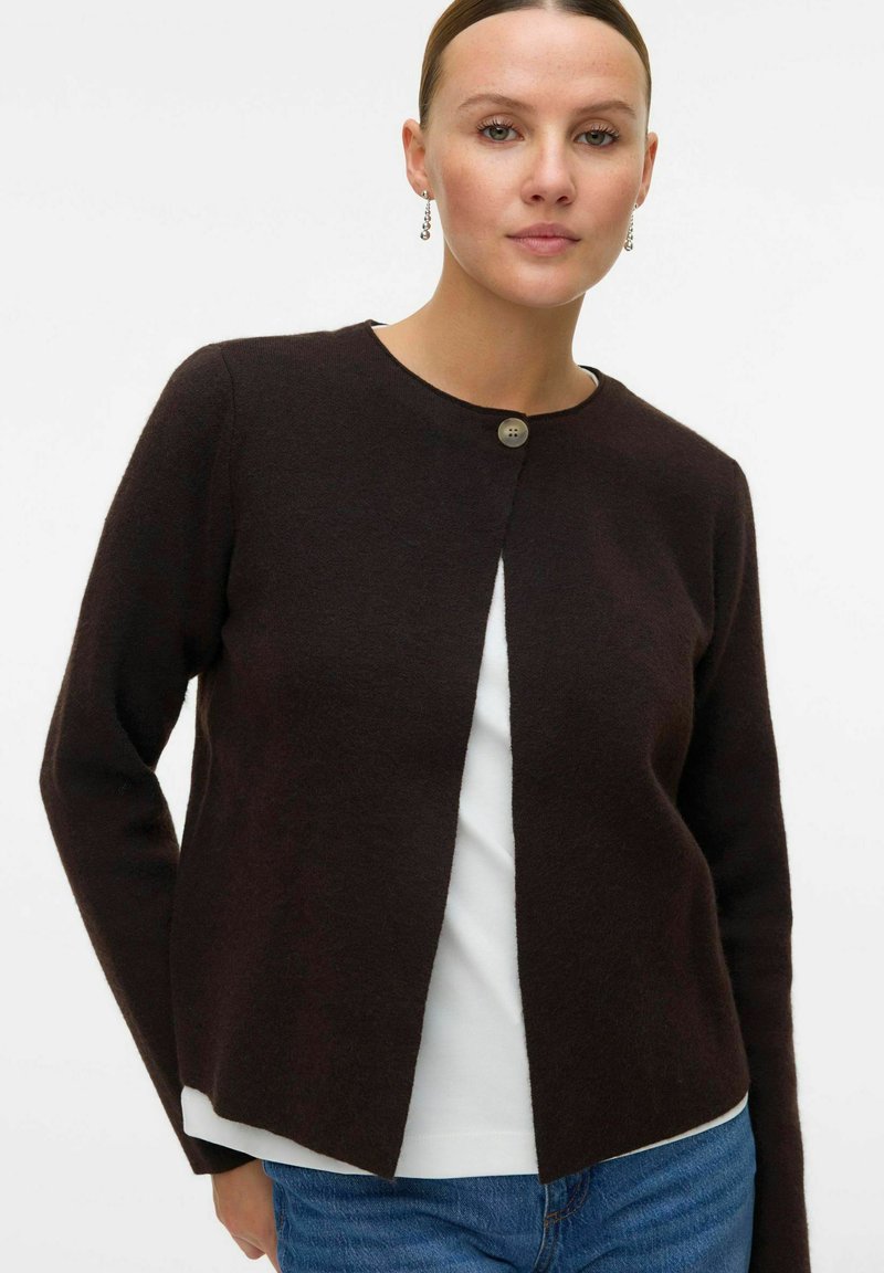 Dunkelbraune Strickjacke aus weichem Material mit runder Halslinie, offener Vorderseite und einem Knopfverschluss. Texturiertes, lässiges Design.