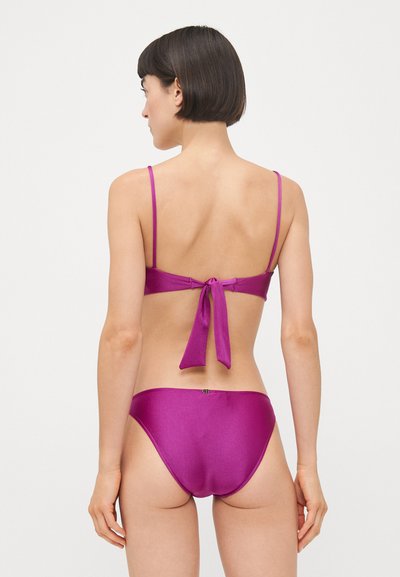 Magenta bikini sett med tynne stropper, med en bindesnor på toppen og sømløse, lave bunn. Glatt, blankt stoff.
