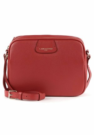 Rode leren schoudertas met textuur, ritssluiting en verstelbare band. Bevat een gouden logo-accent aan de voorkant. Compact rechthoekig formaat.