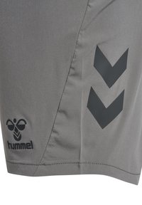 Grijze sportshorts met zwart hummel-logo en twee zwarte chevronpijlen op het rechterbeen.