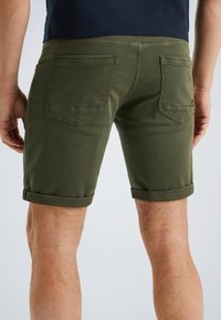 Olijfgroene shorts met opgerolde mouwen, gemaakt van katoen, met twee achterzakken en een subtiel stikselpatroon. Glad van textuur.