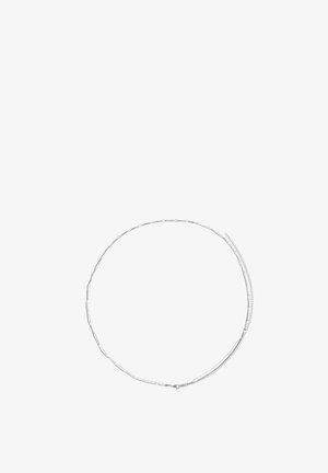 Delicate silver chain necklace with small oval links and a lobster clasp, laid flat in a circular shape on a white background.