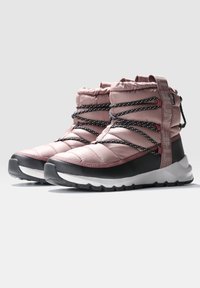 Botas acolchadas de media caña en rosa claro con detalles en negro, que cuentan con cordones a rayas en blanco y negro, una pestaña de tirón y una suela de goma texturizada.