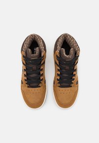 Brązowe zamszowe sneakersy z czarnymi sznurowadłami, wyściełanym kołnierzem i teksturowanym wnętrzem, z perforacjami na palcach dla lepszej wentylacji.