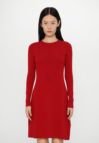 Robe rouge à manches longues en tissu tricot côtelé. Corsage ajusté avec une jupe évasée et col rond. Texture lisse, sans motifs ni accents.