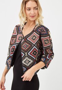 Cárdigan texturizado con diseño geométrico en patrones multicolores, con una base negra, cuello redondo y mangas de tres cuartos.