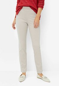 Lys beige bukser med en tætsiddende silhuet og elastisk talje, parret med cremefarvede loafers prydet med en sølvdetalje. Afslappet look.