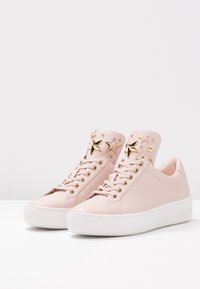 Sneaker in pelle rosa con decorazioni a stella dorate, punta rotonda, suola piatta bianca e chiusura con lacci. Accentuate con hardware in tono dorato.