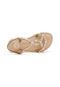 Sandalo in pelle tan con cinturini intrecciati accentuati da perle decorative. Suola piatta con plantare imbottito. Design semplice e aperto all'alluce.