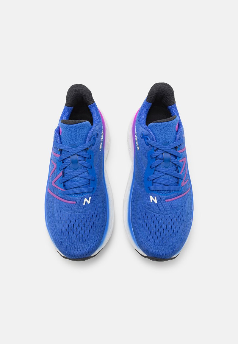 Zapatillas deportivas azules con material de malla, un logo blanco y acentos negros. Presentan una superficie texturizada y una suela acolchada con un degradado púrpura.