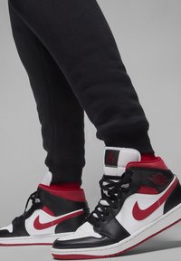 Vysoké tenisky v černo-bílo-červené barevné kombinaci. Kožené a syntetické materiály, s texturovanými akcenty a detaily loga.