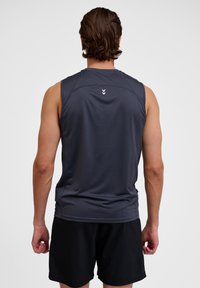 Männer graues ärmelloses Sportshirt aus glattem Stoff, mit Akzenten an den Schulternähten und einem Logo auf dem Rücken. Kombiniert mit schwarzen Shorts.