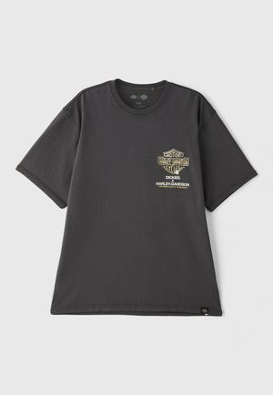 Zwarte katoenen T-shirt met korte mouwen, met een gouden logo op de linkerborst. Rechte zoom en ronde halsdesign.