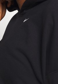 Hoodie noir avec un col montant, tissu doux et logo blanc sur la poitrine. Texture lisse avec une coupe décontractée.