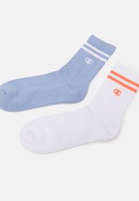 Blaue Socke mit weißen Streifen und Logo; weiße Socke mit orangefarbenen Streifen und Logo. Beide aus weichem, geripptem Material.