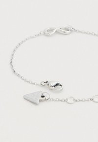 Bracelet en argent avec une chaîne fine, un symbole d'infini et un pendentif triangulaire estampillé d'un logo. Comprend un fermoir mousqueton et des maillons circulaires.