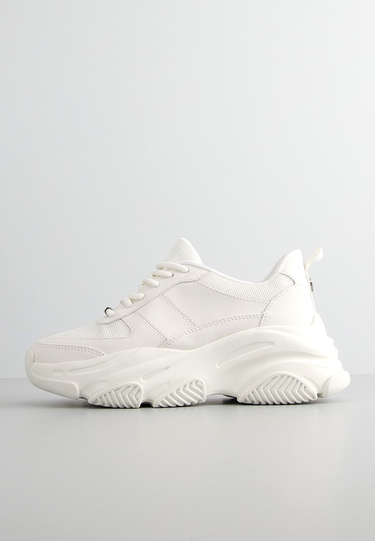 Zapatilla chunky blanca con parte superior de malla, acentos texturizados y una suela de goma gruesa con un agarre estampado. Diseño minimalista con detalles cosidos.