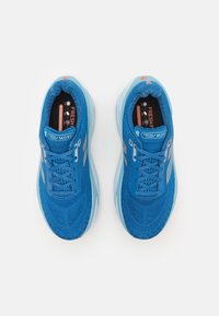 Pantofi sport albaștri cu un material superior din plasă texturată, vârf rotunjit, șireturi plate și talpă căptușită. Include accente reflexive și logo.