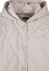 Lyse rosa kviltet jakke med hette, knapper og glatt tekstur, merket "URBAN CLASSICS," størrelse XS.