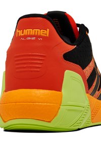 Zwarte en oranje sport schoen met een bovenwerk van textuur stof, een levendig groene zool en een uitgesproken hakontwerp. Merkennaam "hummel" zichtbaar.