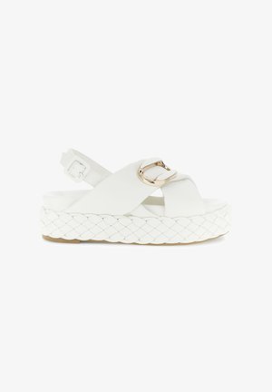 Sandale blanche avec semelle en espadrille tissée, design à lanières croisées, boucle réglable et accent métallique à l'avant. Surface texturée.