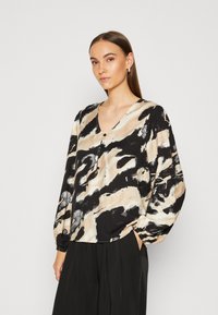 Blusa a maniche lunghe con un motivo astratto beige, nero e bianco, caratterizzata da una scollatura a V e una vestibilità ampia con maniche arricciate.