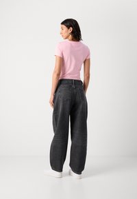 Pink fitted t-shirt and loose-fitting dark gray jeans, with front and back pockets, worn with white sneakers. Simple design, soft texture.