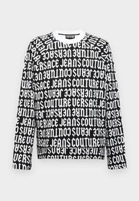 Černobílý sweatshirt s dlouhým rukávem s opakujícím se tučným textovým designem. Kulatý výstřih a volný střih s žebrovanými manžetami.