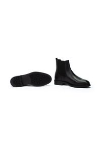 Botas Chelsea de cuero negro con un acabado suave, paneles laterales elásticos y suela de goma con patrones de tracción circulares.