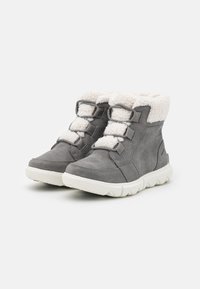 Grå semsket ankelstøvler med hvit faux fur-krage, som har tre elastiske bånd for lukking og en teksturert, hvit gummisåle.