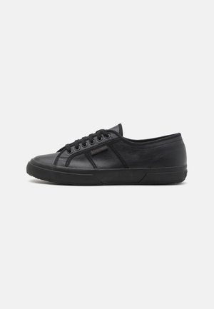 Black sneaker made of textured leather with a low-top design. Features round toe, lace-up front, and rubber sole with a patterned texture.