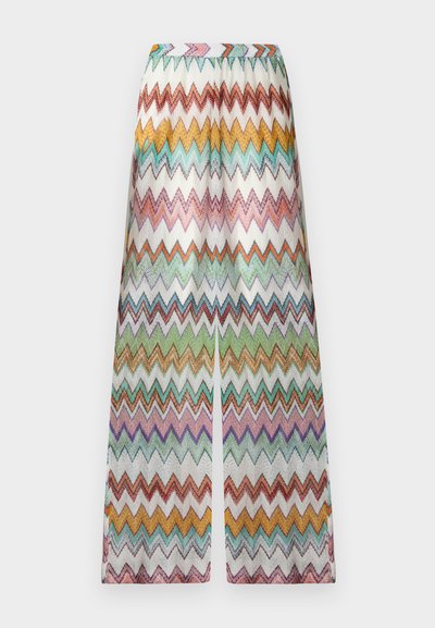 Παντελόνια με φαρδιά μπατζάκια και πολύχρωμες ζιγκ-ζαγκ ρίγες σε πορτοκαλί, κίτρινο, πράσινο, μωβ και τιρκουάζ πάνω σε λευκό φόντο.
